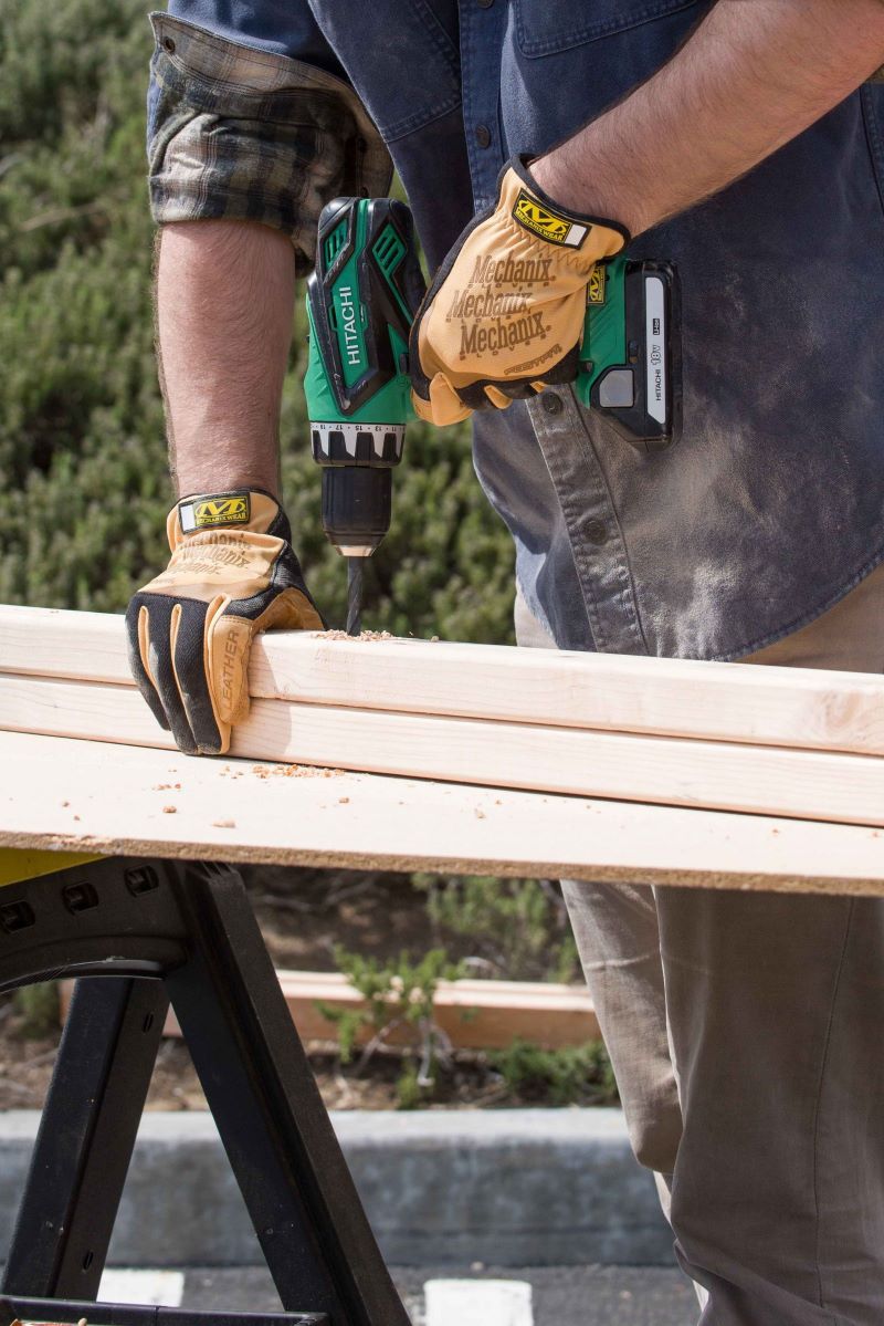 Image of carpenter drilling boards while wearing FastFit gloves.